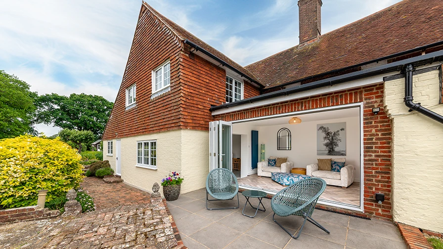 Traditional cottage with bifold doors opening onto a patio seating area and landscaped garden